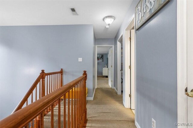 corridor with baseboards, an upstairs landing, light colored carpet, and visible vents