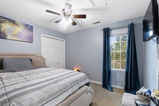 carpeted bedroom with a ceiling fan, attic access, visible vents, baseboards, and a closet