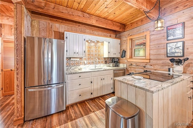 kitchen with pendant lighting, sink, stainless steel fridge, light stone counters, and white cabinetry