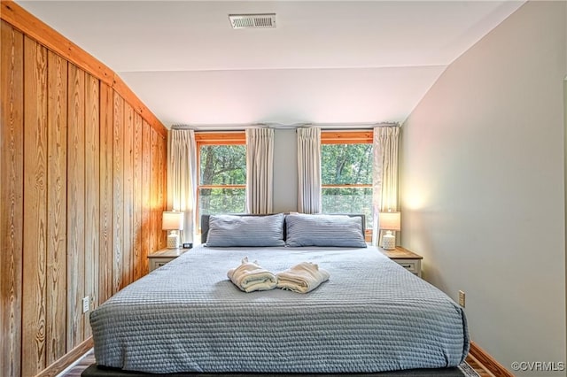 bedroom with lofted ceiling and wooden walls