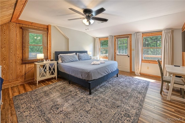 bedroom featuring wood-type flooring, vaulted ceiling, ceiling fan, and wooden walls