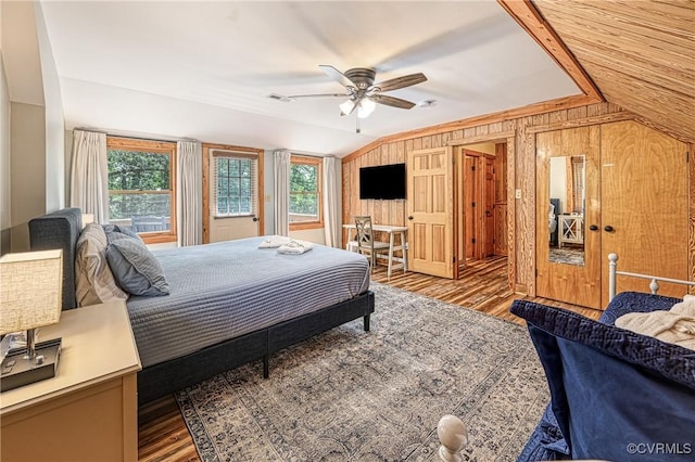 bedroom featuring hardwood / wood-style flooring, vaulted ceiling, ceiling fan, and wood walls