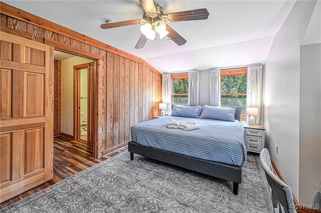 bedroom with ceiling fan, dark hardwood / wood-style floors, lofted ceiling, and wooden walls