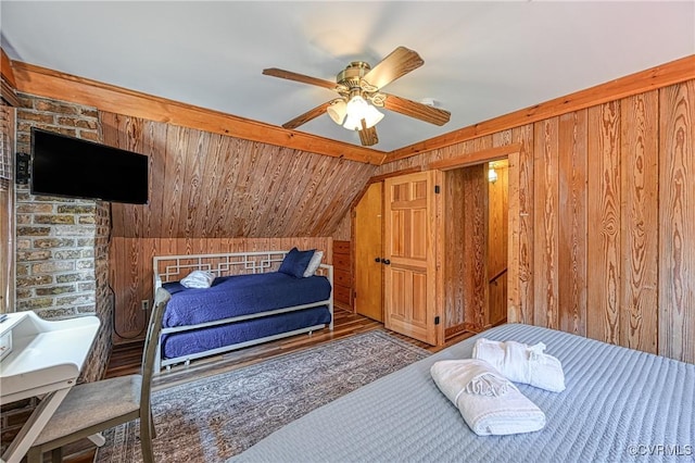 bedroom featuring ceiling fan, wooden walls, wood-type flooring, and vaulted ceiling