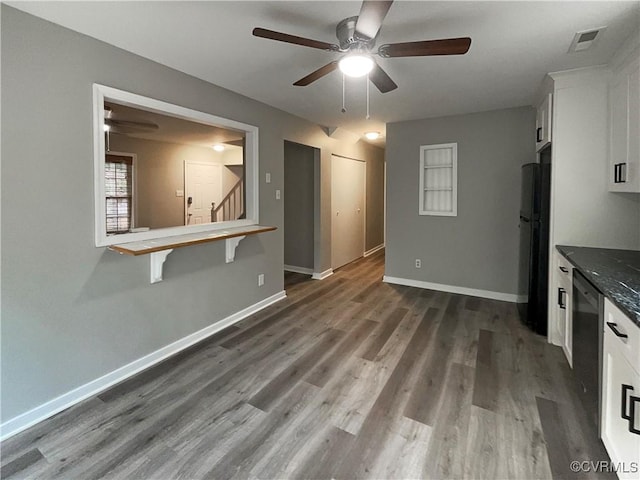 kitchen with white cabinetry, ceiling fan, dark hardwood / wood-style flooring, dark stone countertops, and refrigerator