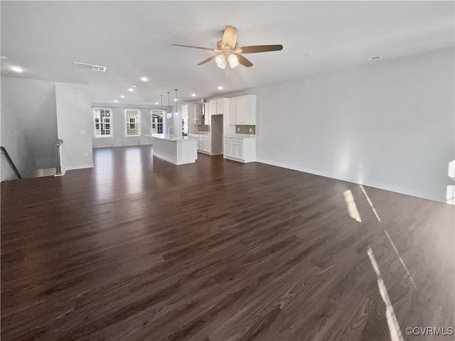 unfurnished living room featuring ceiling fan, dark hardwood / wood-style flooring, and sink