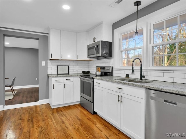 kitchen featuring white cabinets, stainless steel appliances, light hardwood / wood-style floors, and sink