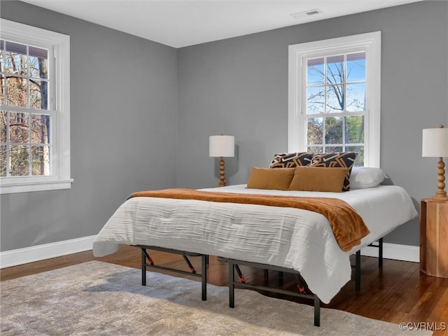 bedroom featuring dark hardwood / wood-style flooring and multiple windows