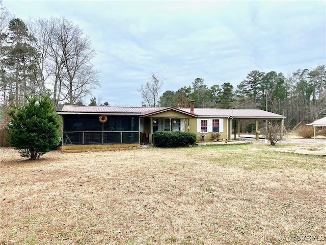 single story home featuring a carport, a sunroom, and a front lawn