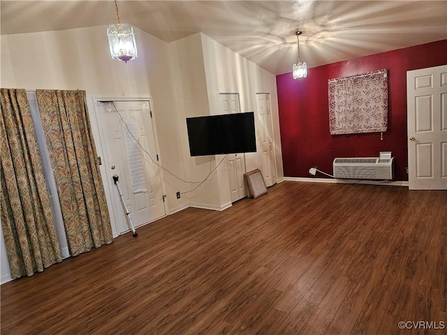 unfurnished living room featuring a notable chandelier, wood-type flooring, and a wall unit AC