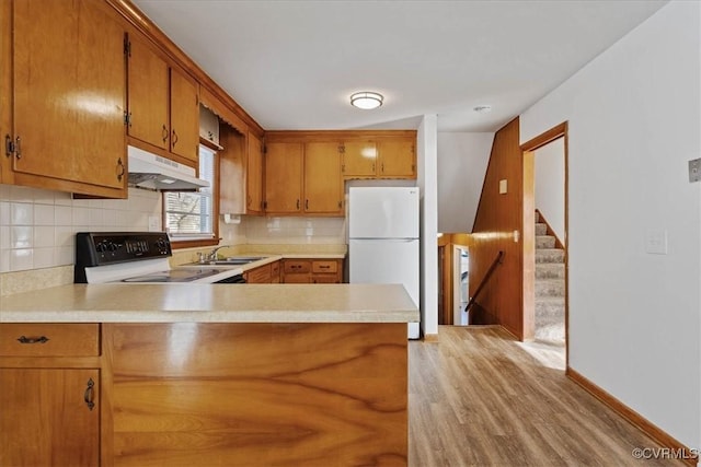 kitchen featuring kitchen peninsula, stove, sink, white refrigerator, and light hardwood / wood-style flooring