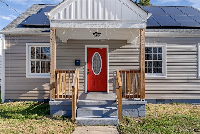 view of exterior entry featuring a yard and solar panels