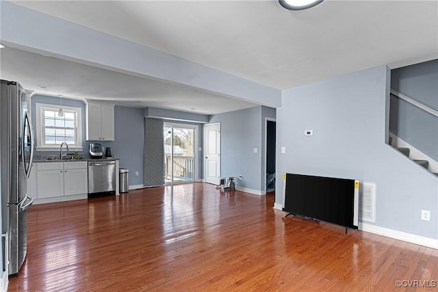 unfurnished living room featuring hardwood / wood-style floors, a wealth of natural light, and sink