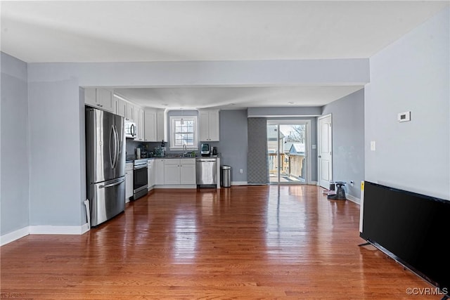 kitchen featuring stainless steel appliances, white cabinetry, hardwood / wood-style flooring, and sink