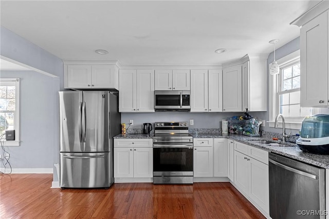 kitchen with sink, light stone counters, appliances with stainless steel finishes, dark hardwood / wood-style flooring, and white cabinetry