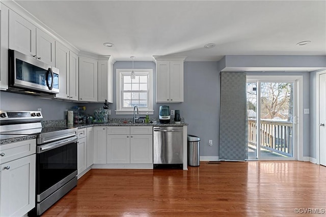 kitchen featuring white cabinetry, dark wood-type flooring, stainless steel appliances, and decorative light fixtures