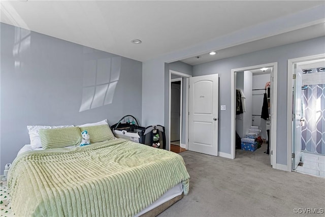 carpeted bedroom with a walk in closet, ensuite bathroom, and a closet