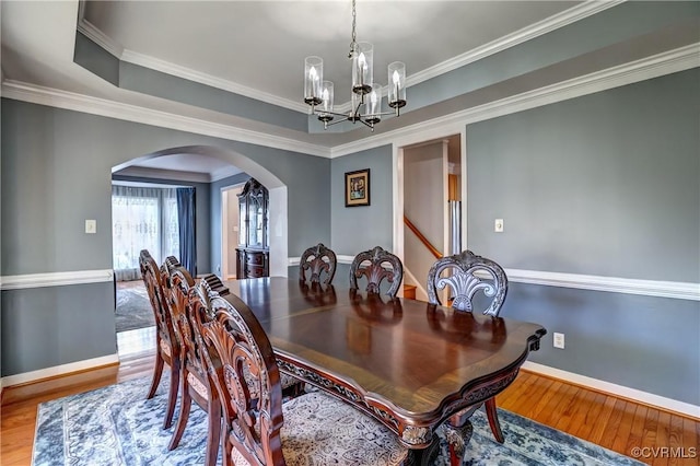 dining room featuring wood-type flooring, crown molding, and an inviting chandelier