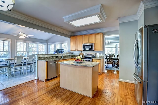 kitchen with ceiling fan, kitchen peninsula, light hardwood / wood-style floors, a kitchen island, and appliances with stainless steel finishes