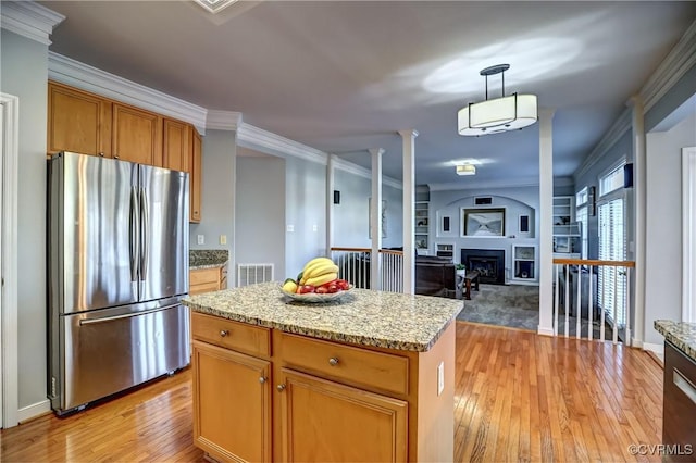 kitchen with built in features, stainless steel fridge, crown molding, pendant lighting, and a kitchen island