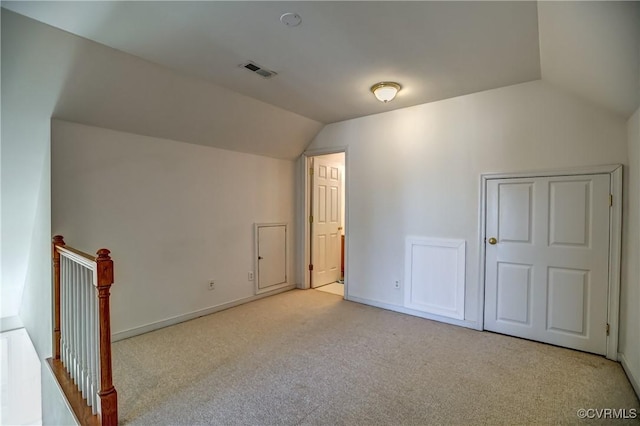 additional living space with light colored carpet and vaulted ceiling