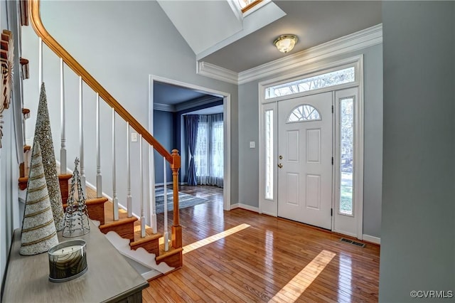 entrance foyer with hardwood / wood-style floors, lofted ceiling, and ornamental molding