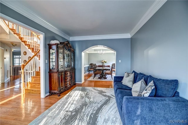 living room featuring wood-type flooring, ornamental molding, and a chandelier