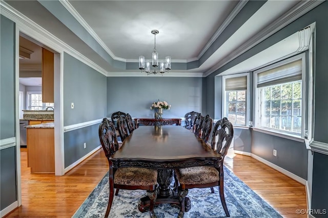 dining area featuring a chandelier, light hardwood / wood-style floors, ornamental molding, and a tray ceiling