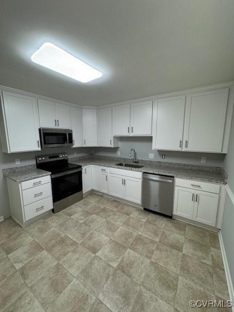 kitchen with white cabinets, sink, light stone countertops, and stainless steel appliances