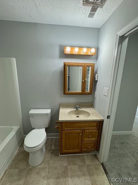 bathroom featuring vanity, a bath, a textured ceiling, and toilet