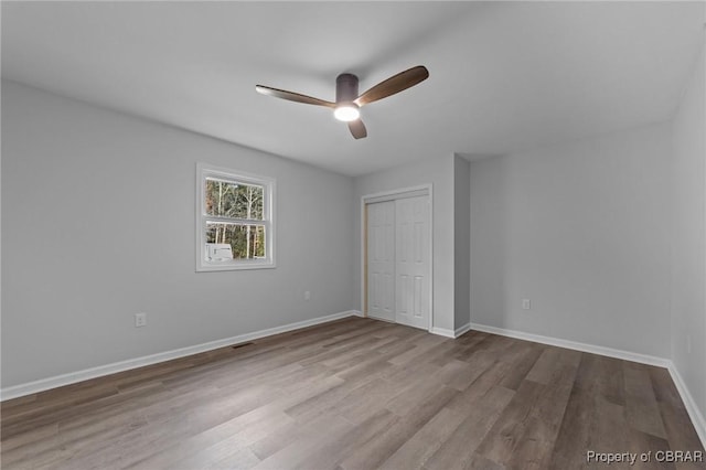 unfurnished bedroom with ceiling fan, light wood-type flooring, and a closet