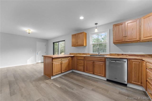 kitchen featuring sink, stainless steel dishwasher, kitchen peninsula, decorative light fixtures, and light wood-type flooring