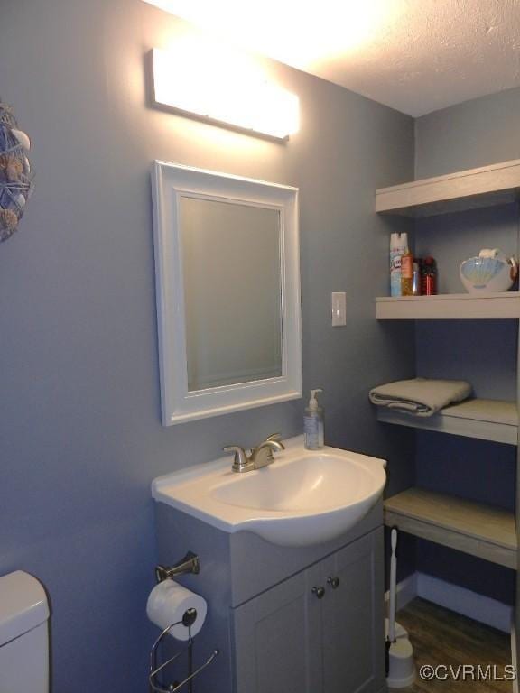 bathroom with vanity, toilet, hardwood / wood-style floors, and a textured ceiling