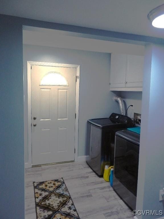 clothes washing area with cabinets and washing machine and dryer