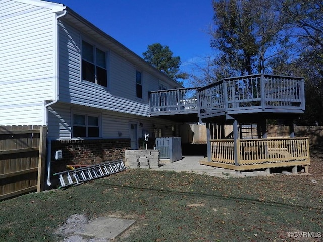 rear view of house with a wooden deck and a lawn