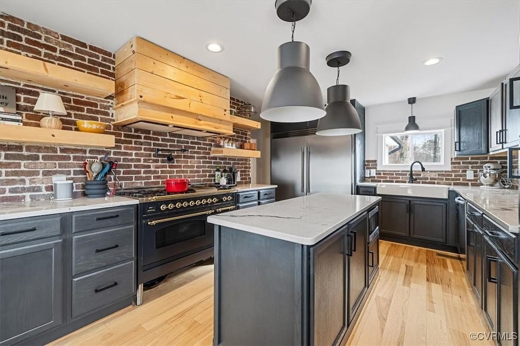 kitchen featuring light stone counters, custom exhaust hood, sink, built in appliances, and a kitchen island