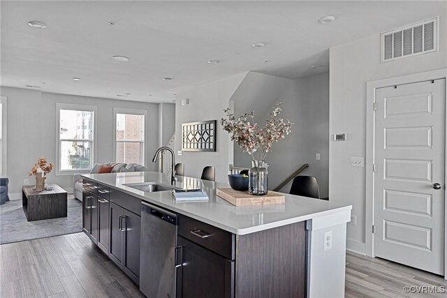 kitchen with sink, dark brown cabinets, stainless steel dishwasher, and an island with sink