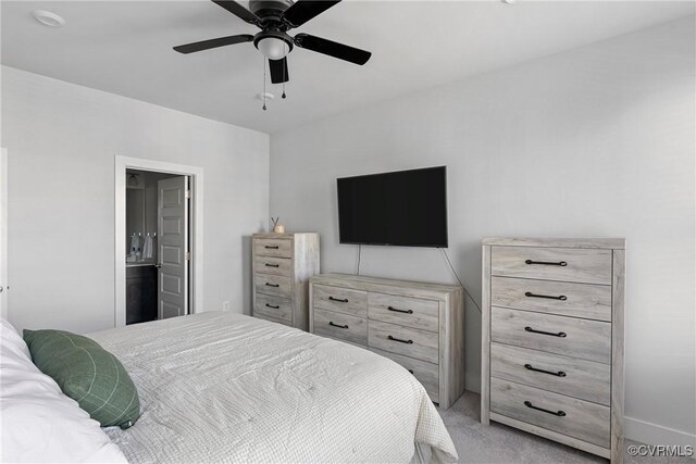 bedroom with ensuite bathroom, light carpet, and ceiling fan