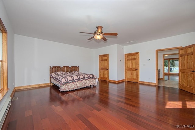 bedroom with ceiling fan, baseboard heating, and dark wood-type flooring