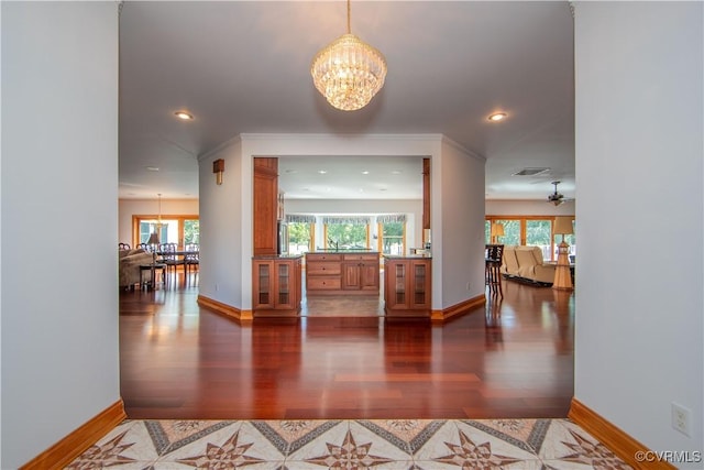 corridor featuring a wealth of natural light, dark hardwood / wood-style floors, and a notable chandelier