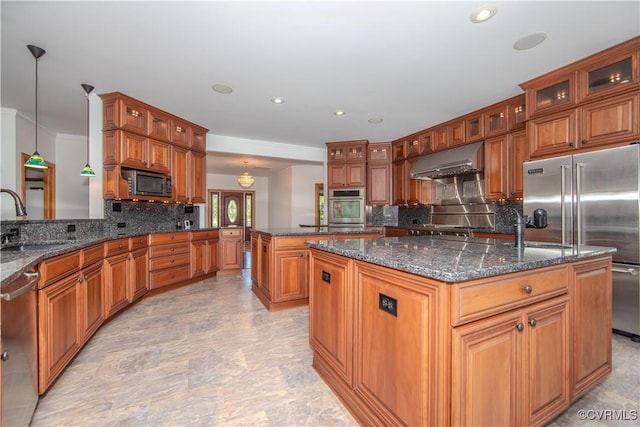 kitchen featuring ventilation hood, sink, hanging light fixtures, built in appliances, and an island with sink