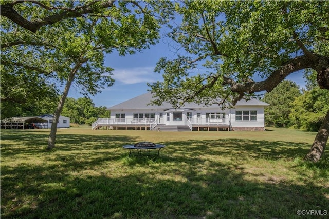 back of property featuring a lawn, an outdoor fire pit, and a wooden deck