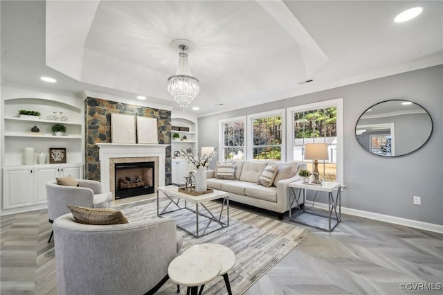 living room featuring built in features, a fireplace, a chandelier, light parquet floors, and ornamental molding