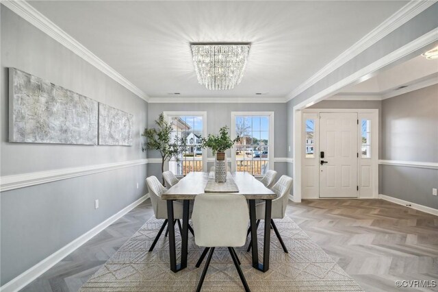 dining area with light parquet floors, ornamental molding, and a notable chandelier