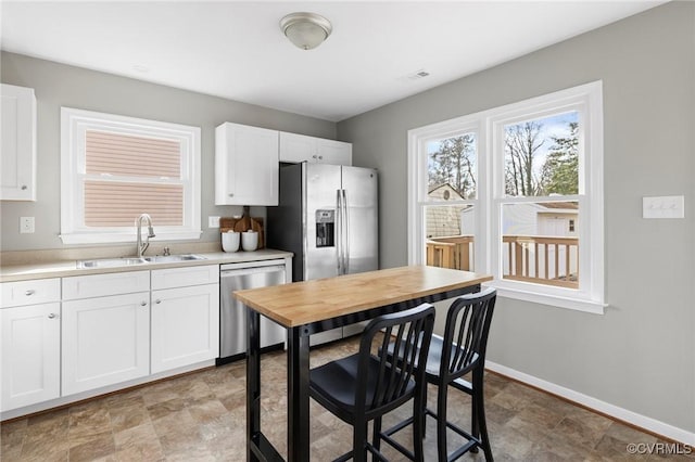 kitchen with appliances with stainless steel finishes, white cabinetry, and sink