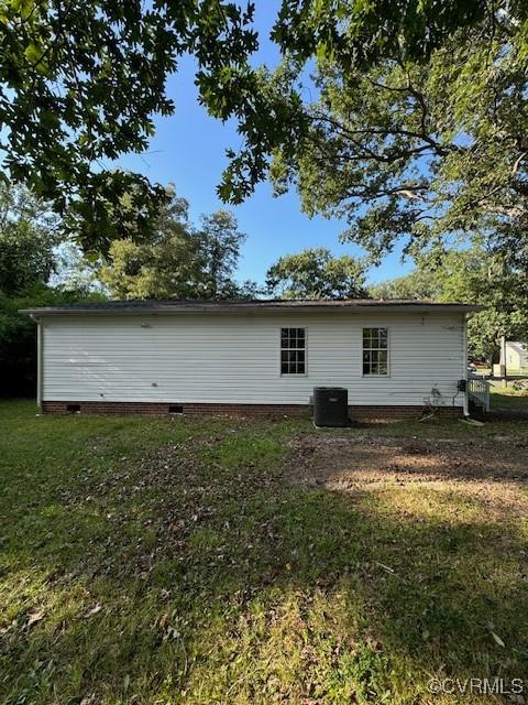 back of property featuring a lawn and central AC