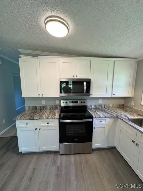 kitchen with stone counters, white cabinets, crown molding, light wood-type flooring, and stainless steel appliances