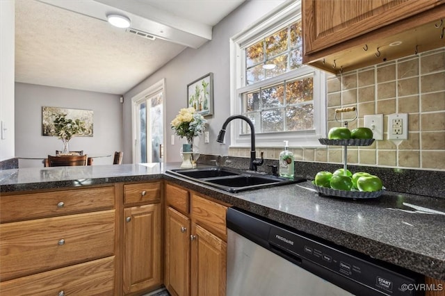 kitchen with decorative backsplash, stainless steel dishwasher, dark stone counters, and sink