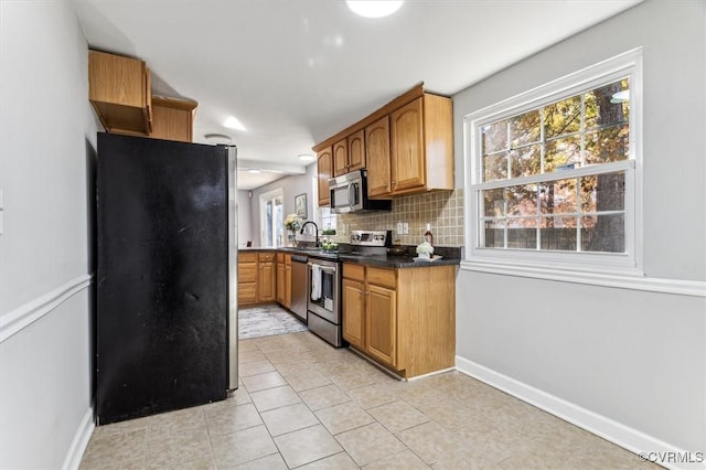 kitchen with light tile patterned flooring, appliances with stainless steel finishes, backsplash, and sink