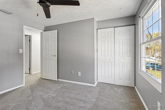 unfurnished bedroom with ceiling fan, a closet, light carpet, and a textured ceiling